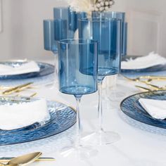 the table is set with blue dishes and gold place settings