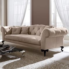 a living room filled with furniture next to two windows and a rug on the floor