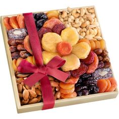 an assortment of nuts and dried fruits in a wooden box with a red ribbon tied around it