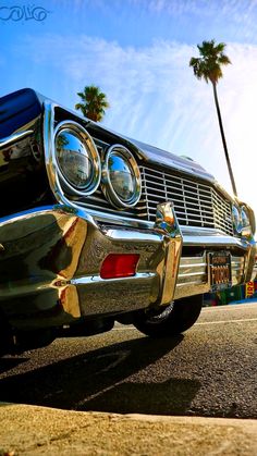 an old car parked on the side of the road with palm trees in the background