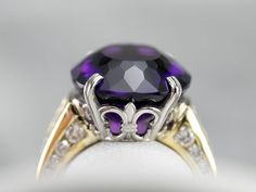 This stunning amethyst cocktail ring has a deep purple amethyst in the center, that really flashes and flickers with vibrant violet reflections! Two rows of square-cut diamonds add sparkle, while round-cut diamonds line the shank of the yellow gold band. Set into a lovely mounting with structurally designed shoulders and a fleur de lis platinum head, this bold statement ring is a beautiful addition to anyone’s collection! Metal: 18K Yellow Gold, Platinum Gem: Amethyst 12.48 Carats Gem Measuremen Yellow Gold Sapphire Ring, Amethyst Cocktail Ring, Gold Amethyst Ring, Demantoid Garnet, Crystal Goddess, Diamond Cocktail Ring, Diamond Cocktail Rings, Purple Band, Square Cut