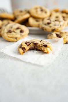 chocolate chip cookies are on paper towels next to a cookie tin with more cookies in the background