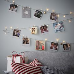 a bed with pictures hanging on the wall and wrapped presents under lights next to it