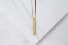 "This is as easy as it gets. A simple solid brass bar (1 1/8\" tall), strung directly onto an aged brass chain (nickel free). Bar necklaces are very cool and what I love about this one is the length and color of the coordinating chain. I designed the necklace to be long but not too long, bright but not flashy, and it has to go with everything. It has a little weight to it. It's not just a flat piece of metal - it's solid brass, with smooth edges and a minimal meets modern feel. *If you prefer a Minimalist Gold Rectangular Bar Necklace, Minimalist Brass Necklace With Rectangular Pendant, Classic Rectangular Gold Bar Necklace, Minimalist Personalized Rectangular Bar Necklace, 14k Gold Rectangular Pendant Bar Necklace, Minimalist Yellow Gold Bar Necklace With Rectangular Pendant, Gold Bar Pendant, Vertical Bar, Minimalist Men