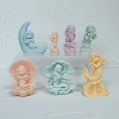 there are seven little figurines in the shape of moon and mermaids on display