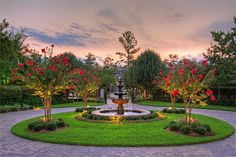 a garden with a fountain surrounded by trees and flowers