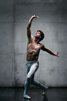 a man in white and blue is dancing on the floor with his arms stretched out