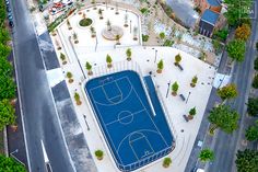 an aerial view of a basketball court in the middle of a parking lot with lots of trees