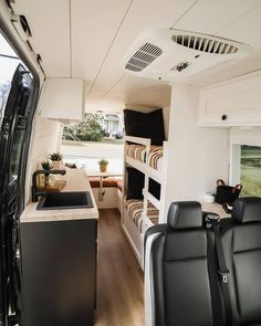 the interior of a bus with black seats and wood flooring on the outside wall