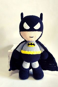 a crocheted batman doll is posed on a white background