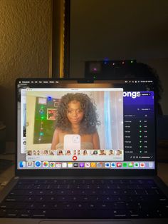 an open laptop computer sitting on top of a wooden desk next to a window with the image of a woman's face