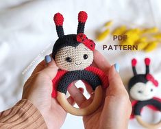 a crocheted ladybug doll is being held by someone's hand