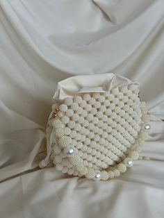 🌟 Elevate your style with this exquisitely crafted handbag adorned with pearl details. 🌟 Handcrafted with care, this bag is designed to add a touch of sophistication to every moment. The elegance of the pearl embellishments sets this bag apart, transforming it into a unique accessory. 🌸 Why Choose This Bag? 🌸 More than just an accessory, this bag is an opportunity to reflect your style and grace. Whether for a special event or to enhance your daily chic, this pearl-adorned bag complements ev Cream Evening Bag With Pearl Handle As Gift, Cream Evening Bag With Pearl Handle For Gift, Cream Bags With Pearl Embroidery For Events, Handmade Cream Bag For Events, Handmade Cream Bags For Events, Luxury Bags With Pearl Embroidery, Handmade Pearl Evening Bag In Cream, Handmade Cream Pearl Evening Bag, Beaded Cream Shoulder Bag For Gift