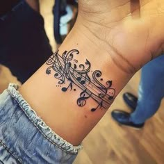 a woman's wrist tattoo with musical notes and music notes on the side of her arm