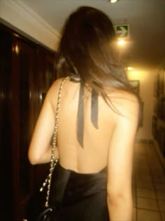 the back of a woman's dress with a black bow tie on her neck