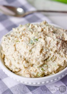 a white bowl filled with chicken salad on top of a purple and white checkered table cloth