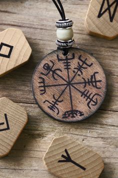 a wooden pendant with writing on it sitting next to some dices and beads,