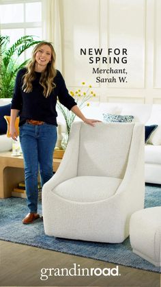 a woman standing next to a white chair in a living room with blue rugs