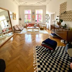 a living room filled with furniture and a large mirror on the wall next to it