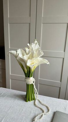 a bouquet of white flowers with pearls on a table