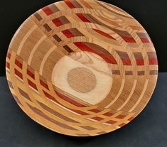 a wooden bowl with red, brown and white designs on the bottom is sitting on a black surface