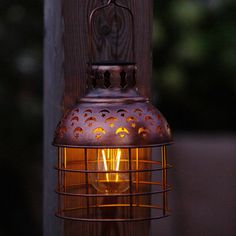 an old fashioned lamp hanging from a wooden post with the light on it's side