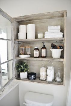 a bathroom shelf filled with toilet paper and other items next to a window in the corner