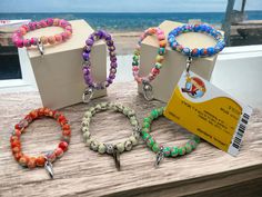 three bracelets with different colors and designs are on display in front of the ocean