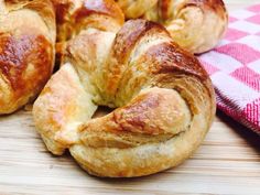 several croissants sitting on top of a wooden table next to a red and white checkered cloth