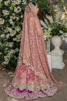 a woman in a pink lehenga standing next to flowers