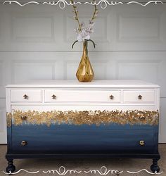 a blue and white dresser with gold paint on it