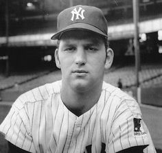 a black and white photo of a baseball player wearing a new york yankees uniform in an empty stadium