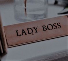 a lady boss sign sitting on top of a table next to a glass filled with water