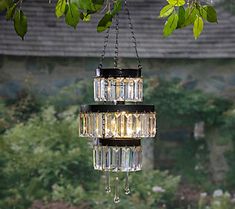 a chandelier hanging from a tree branch in front of a building and trees