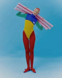 a woman in a bodysuit holding two large pink objects on her head and wearing red shoes