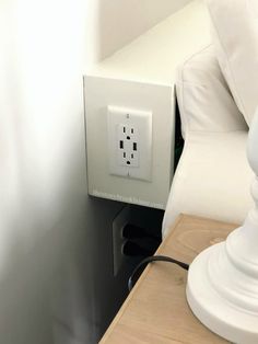 a white light switch sitting on top of a wooden table next to a lamp shade