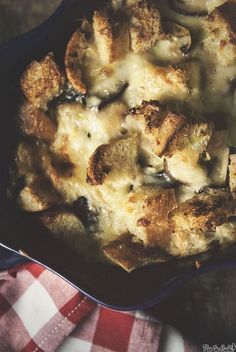 a casserole dish with mushrooms and cheese in it sitting on a checkered cloth