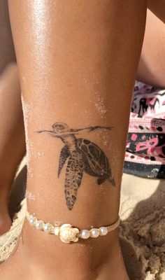 a woman's foot with a turtle tattoo on her ankle and pearls around the ankles