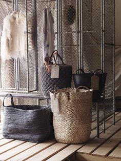 three baskets are sitting on the floor in front of a rack with coats and purses