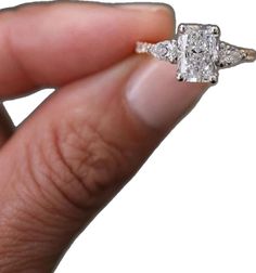 a woman's hand holding an engagement ring with two diamonds on it and the other side