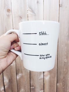 a person holding a coffee mug with words on the inside and outside of it that read shh almost now you may speak