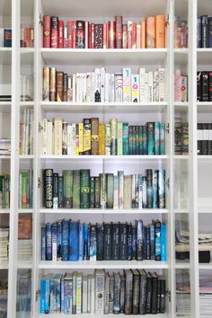 a book shelf filled with lots of books on top of white shelving unit shelves