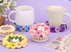 crocheted coffee cups and coasters on a table with flowers in them,