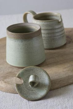 two mugs sitting on top of a wooden board