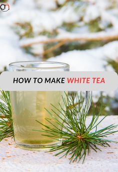 a glass cup filled with white tea sitting on top of a table covered in snow