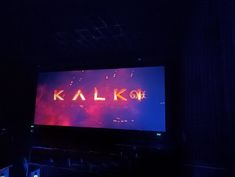 a large screen with the word kala koh on it in front of a dark room