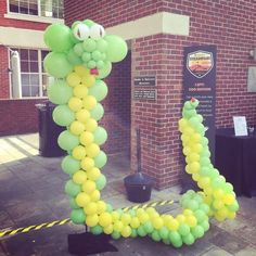 there is a large balloon shaped like a snake on the ground in front of a brick building