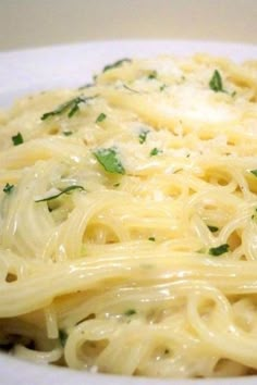 a plate of pasta with parmesan cheese and fresh herbs on the top is ready to be eaten