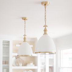 two lights hanging from the ceiling above a dining room table with flowers in vases