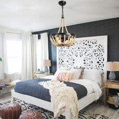 a bedroom with black walls and white bedding, rugs on the floor, two chairs